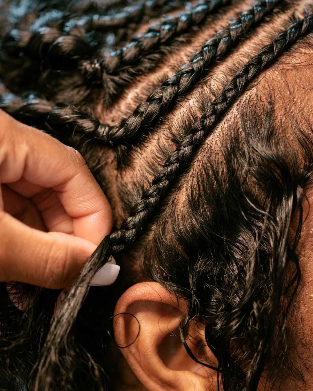 Braided hair being styled by hand, close-up view showing intricate detailing.